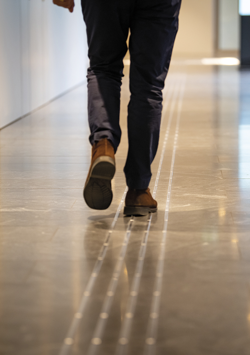 A male person in brown shoes walking down the hallway.