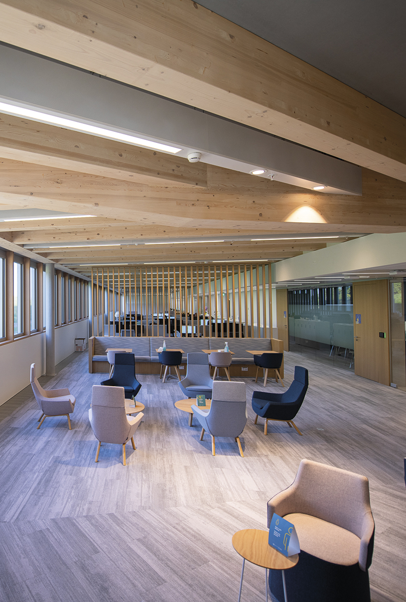 Lounge area in the new office building with blue and gray armchairs and chairs and wooden tables.